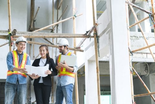 young asian engineers teamwork site inspector discuss together using notebook computer paper blueprint building construction sitehome renovation ideas concept
